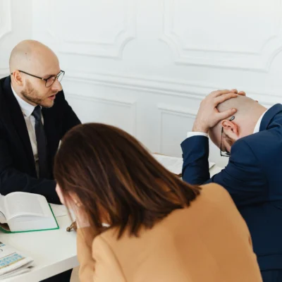 Legal professionals engaged in a tense meeting at a law office with open documents on the desk.